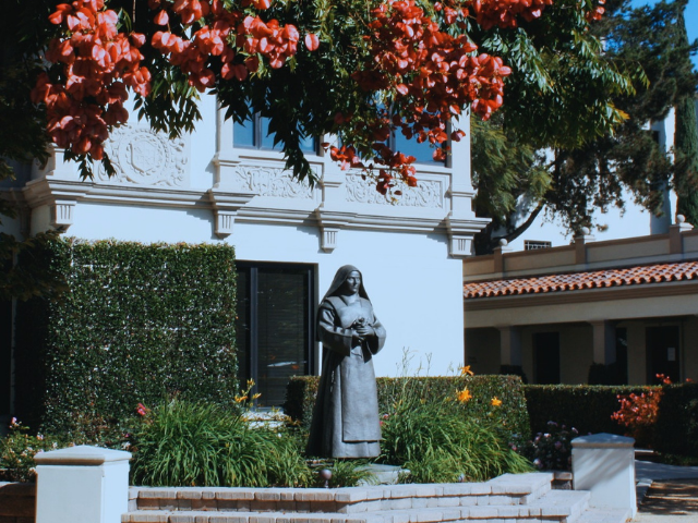 statue of a Catholic nun standing in a beautiful garden