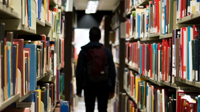 someone walking through the stacks of books at a library