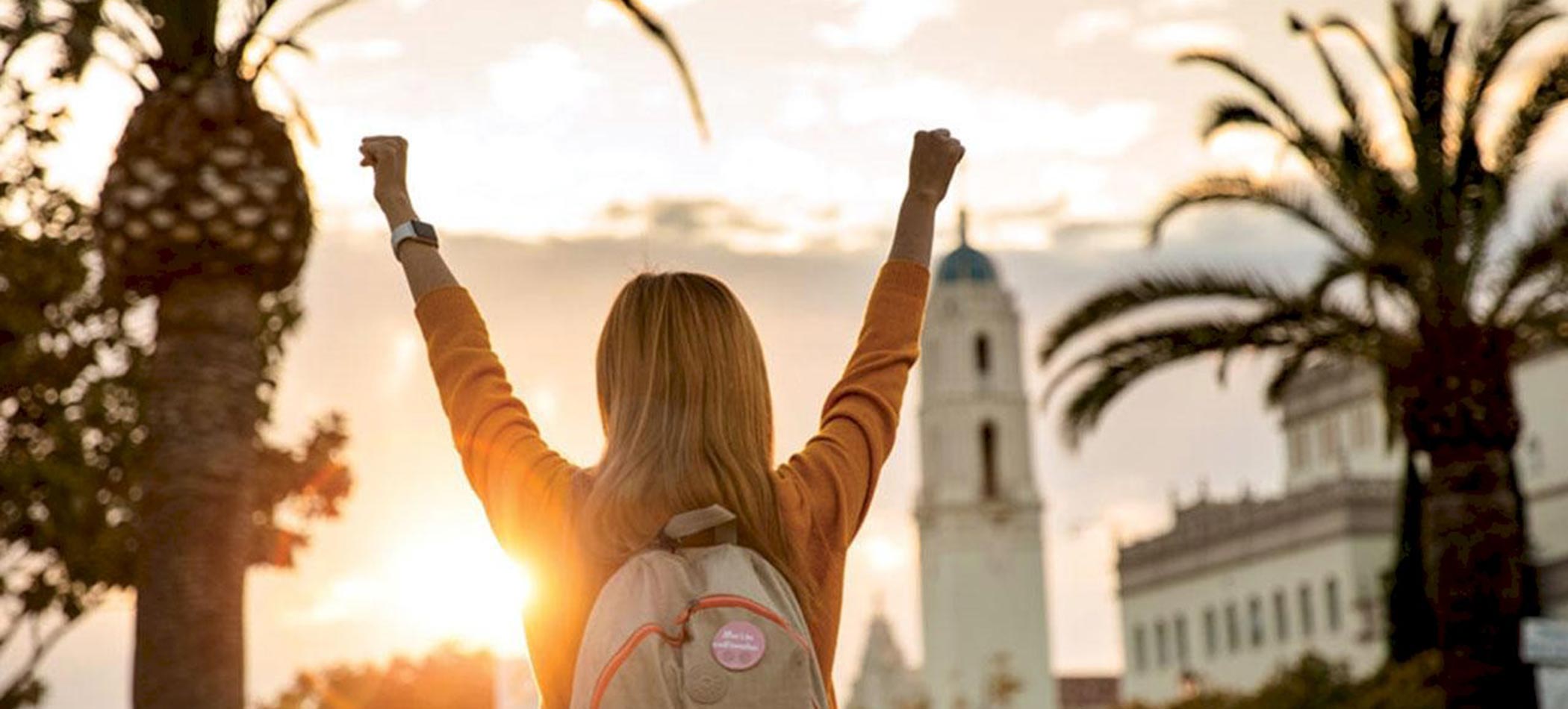 a student in front of the immaculata and the sunset
