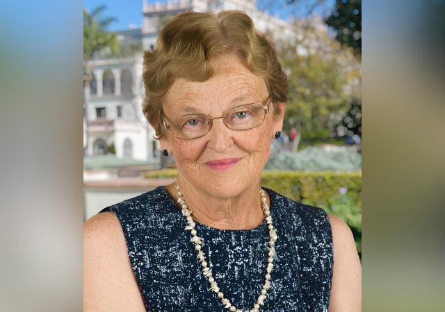 Headshot of Florence in a sleeveless black top, long strand of beads and her head tilted slightly.