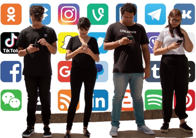 Four young adults, looking down at their cell phones in their hands with social media logos in the background