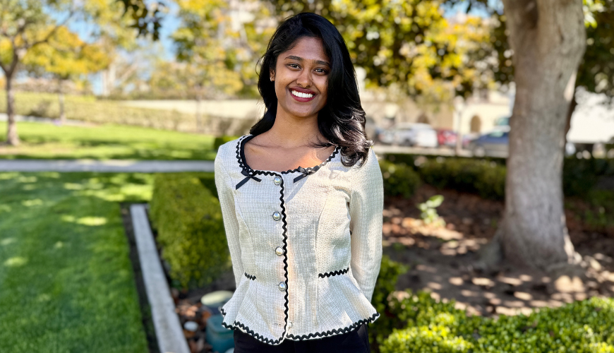 Sumayya Sirajudeen sits smiling in front of a water fountain near the Immaculata Church.