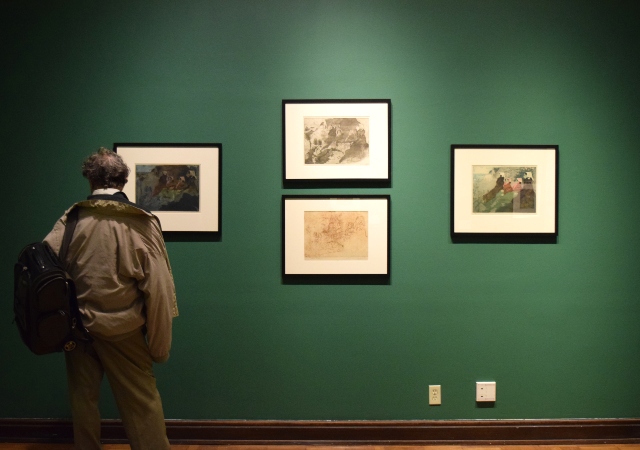 Adult viewing four prints hanging on a wall.