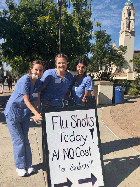 Nursing students in front of free flu shot sign
