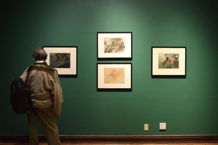 Adult viewing four prints hanging on a wall.