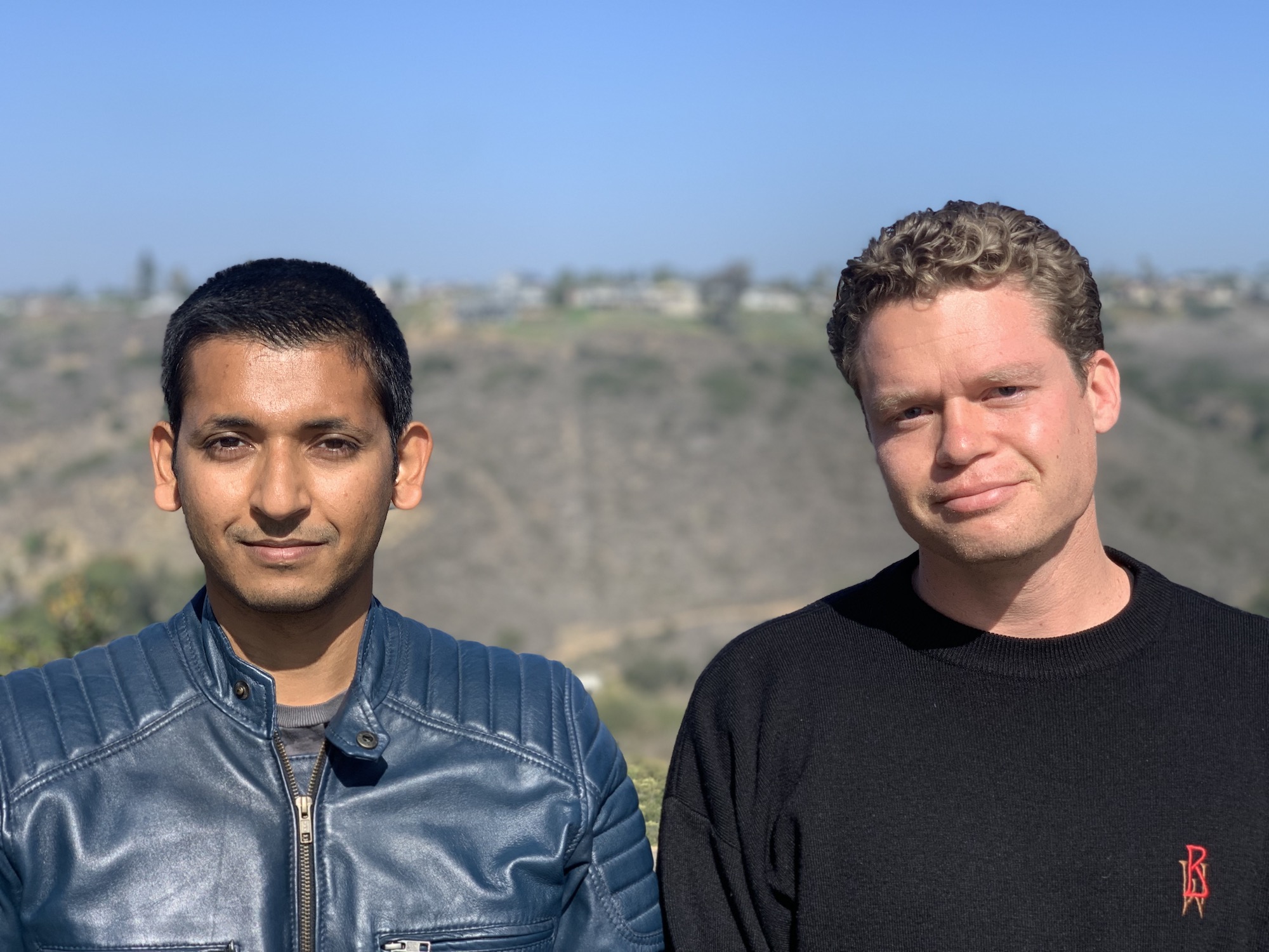 Abhi Sharma and Mark Murphy stand together with a blurry hillside in the background