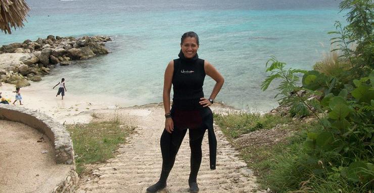 Dr. Brito-Millan stands at the beach wearing a wet-suit.