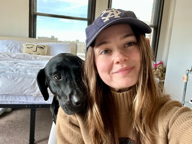 Helayna smiles at the camera while sitting next to her dog.