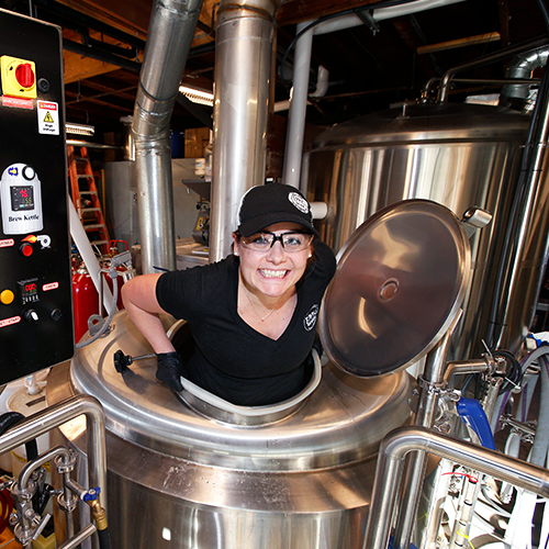 USD alumna Stephanie Eppig popping out of a barrel at her brewery, Eppig Brewery