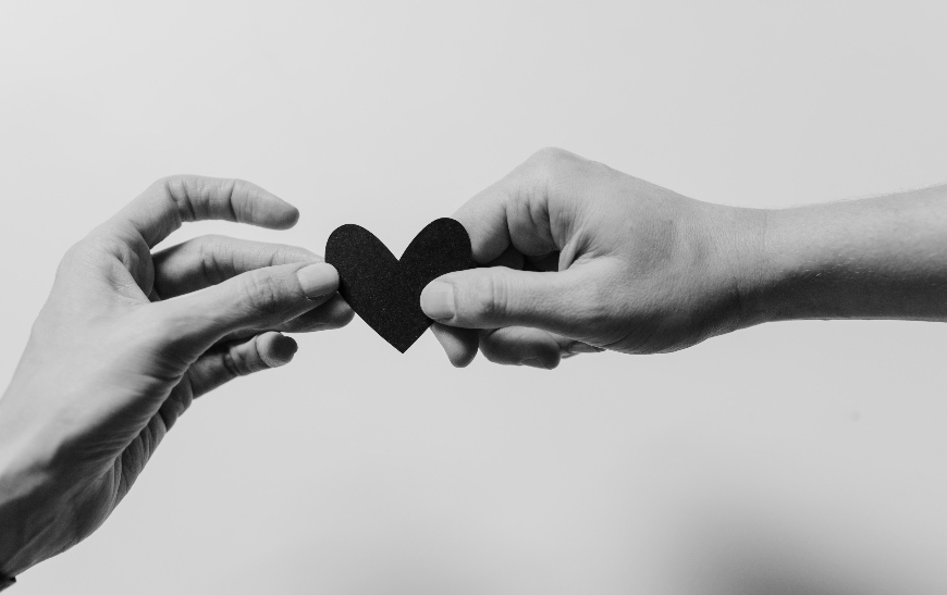 a hand passing a heart to another hand