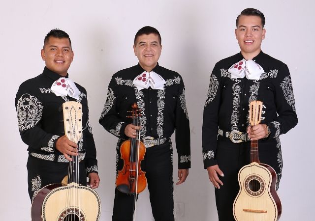 Trio Jalisco en la Piel posing with their guitars and violin