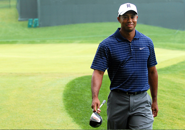 Tiger Woods smiling on a golf course.