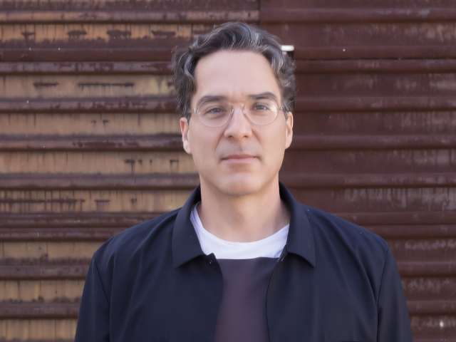 Marcel Sanchez Prieto standing in front of US-Mexico border.