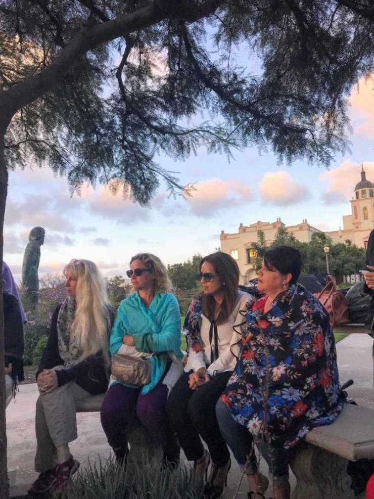 four women sitting on a bench outside