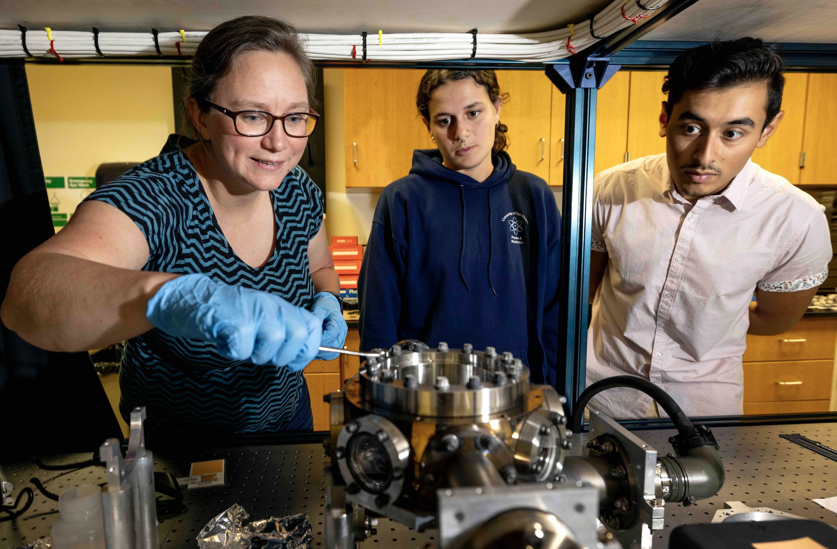 Dr. Maren Mossman leaning over research project with two students.