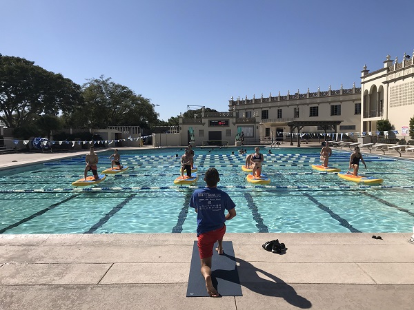 Students practicing paddleboard yoga with an instructor at the Sports Center pool