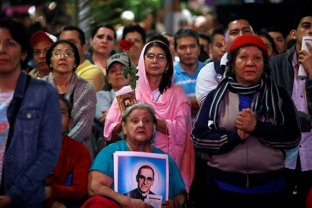 Crowd holding photos of St. Oscar Romero at a rally