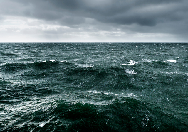 surface of the middle of the ocean with dark gray clouds above
