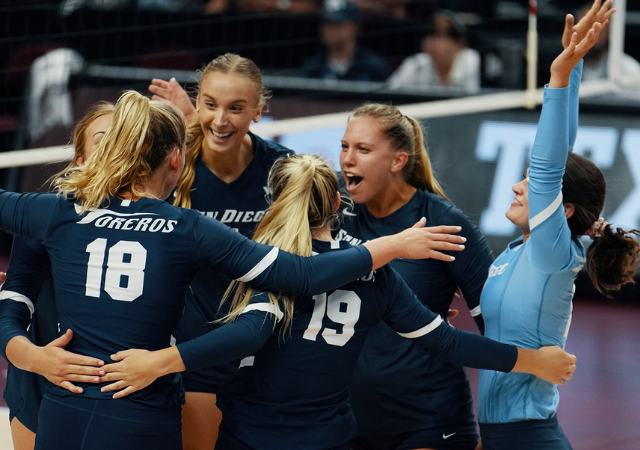 Female players celebrating on volleyball court.