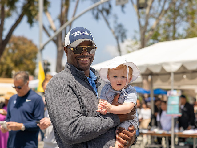 USD Football Coach Brandon Moore poses with a young fan