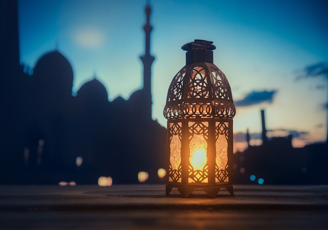 Image of a lit candle with a towers in the background