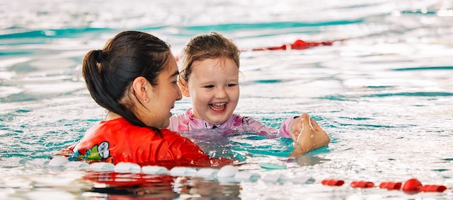 child in pool with swim instructor