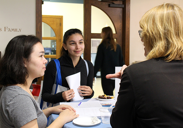Photo of two students talking and networking with a professional