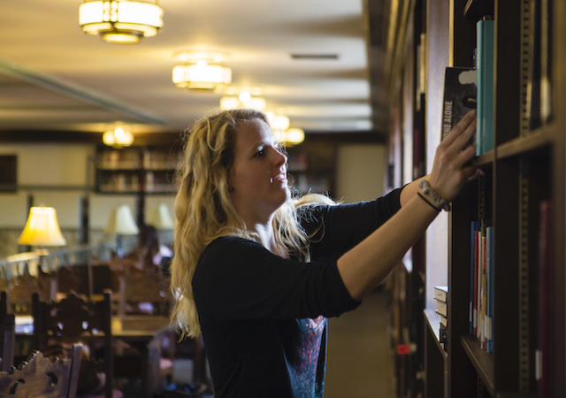 student pulling books off shelf in Copley Library