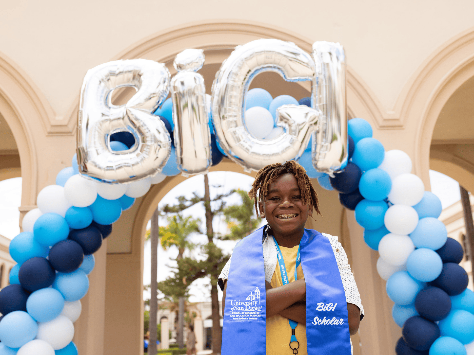 BiGI scholar standing in front of BiGI balloon arch