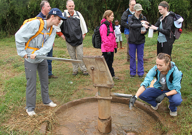 USD students pump water out to run quality testing on it in Uganda.