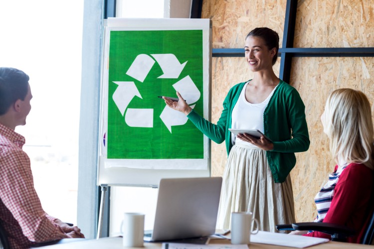 A woman at a white board presents a recycling initiative.