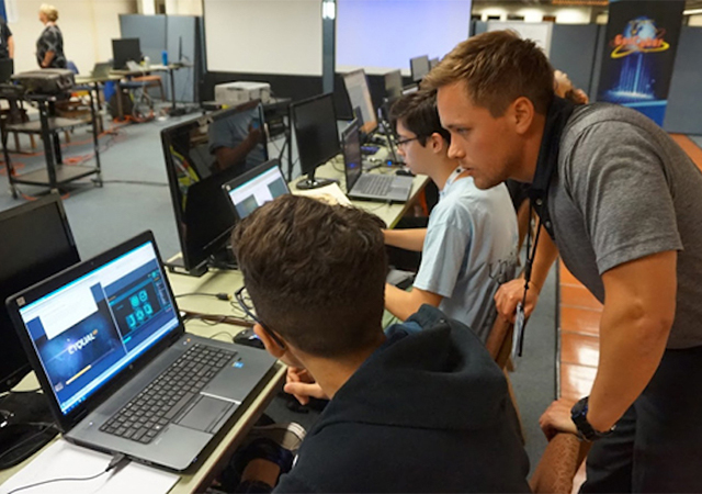 An instructor looks on as a student seeks advice during the USD Cybersecurity Law Enforcement Investigations and Digital Forensics Camp.