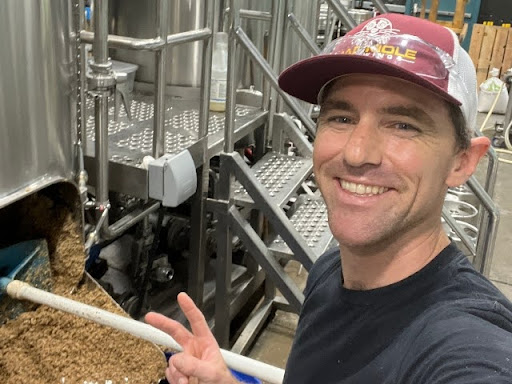 Dano Ferons smiling in front of the brewing equipment at Mad Mole Brewery
