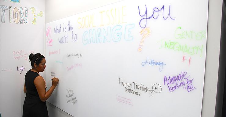 Bianca Alvarado, a student in the new MA in Social Innovation degree program in the Kroc School, answers a question on the wall of the new Wasson Social Innovation Lab space at USD.