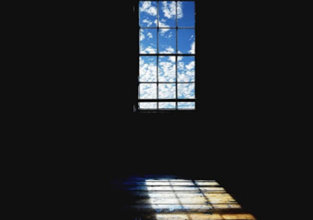 image of a dark room with blue sky and clouds visible through a window