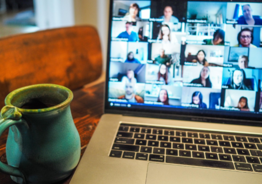 A laptop during a webinar next to a coffee mug