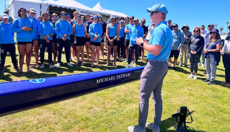 USD Men's Rowing Coach Bart Thompson stands in front of one of the team's boat shells at the San Diego Crew Classic.