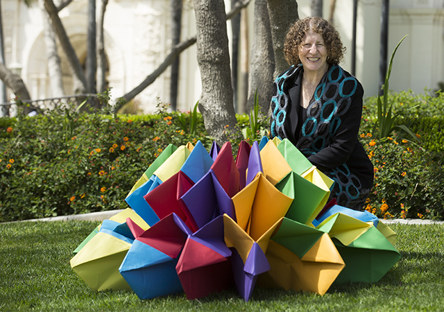 Perla Myers, part of Project VisMo, poses with a large origami piece