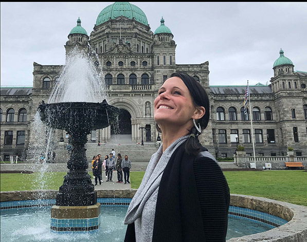 Dr. Waniac, smiling, face upwards, in front of a fountain.