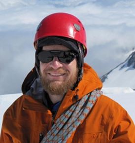 Dr. Richard Alley stands in the field with a helmet and other equipment.