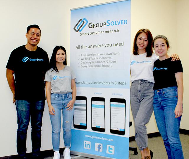 USD alumni smile in front of GroupSolver sign