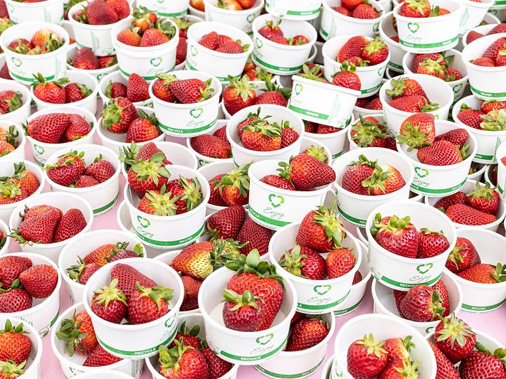 Numerous small servings of whole strawberries.