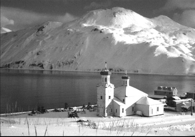 An old photograph of some buildings next to the ocean in an icy landscape