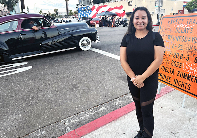 Amaya Ardilla posing on a street with a lowrider in the background