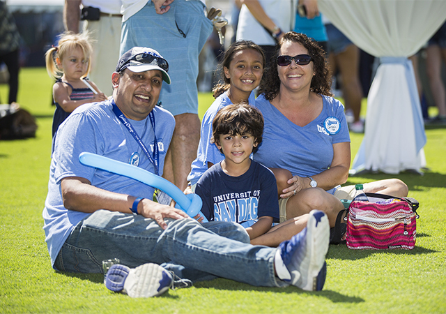 Torero parents sitting on the grass with kids