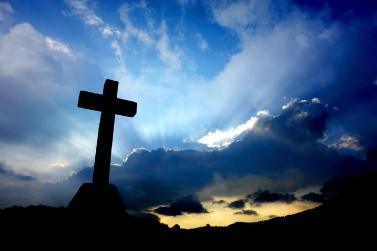 cross with dark sky and mountains in background