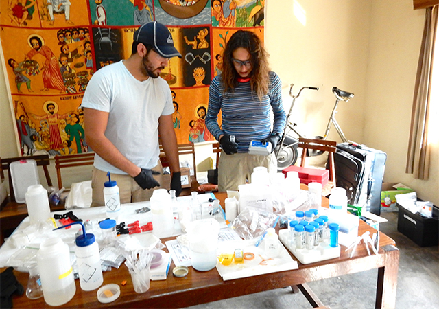 Students on a past trip to Uganda work on water samples in a makeshift lab.