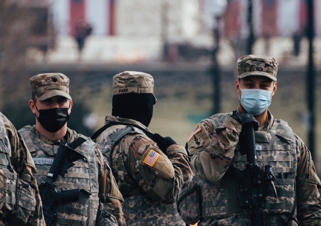 National Guards wearing face masks and standing armed in front of the US capitol building