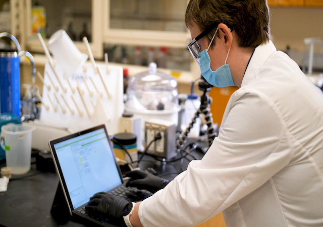 faculty member with mask working at a computer