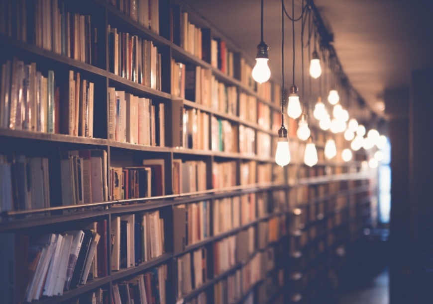bookshelf in a library with hanging wires and single lightbulbs